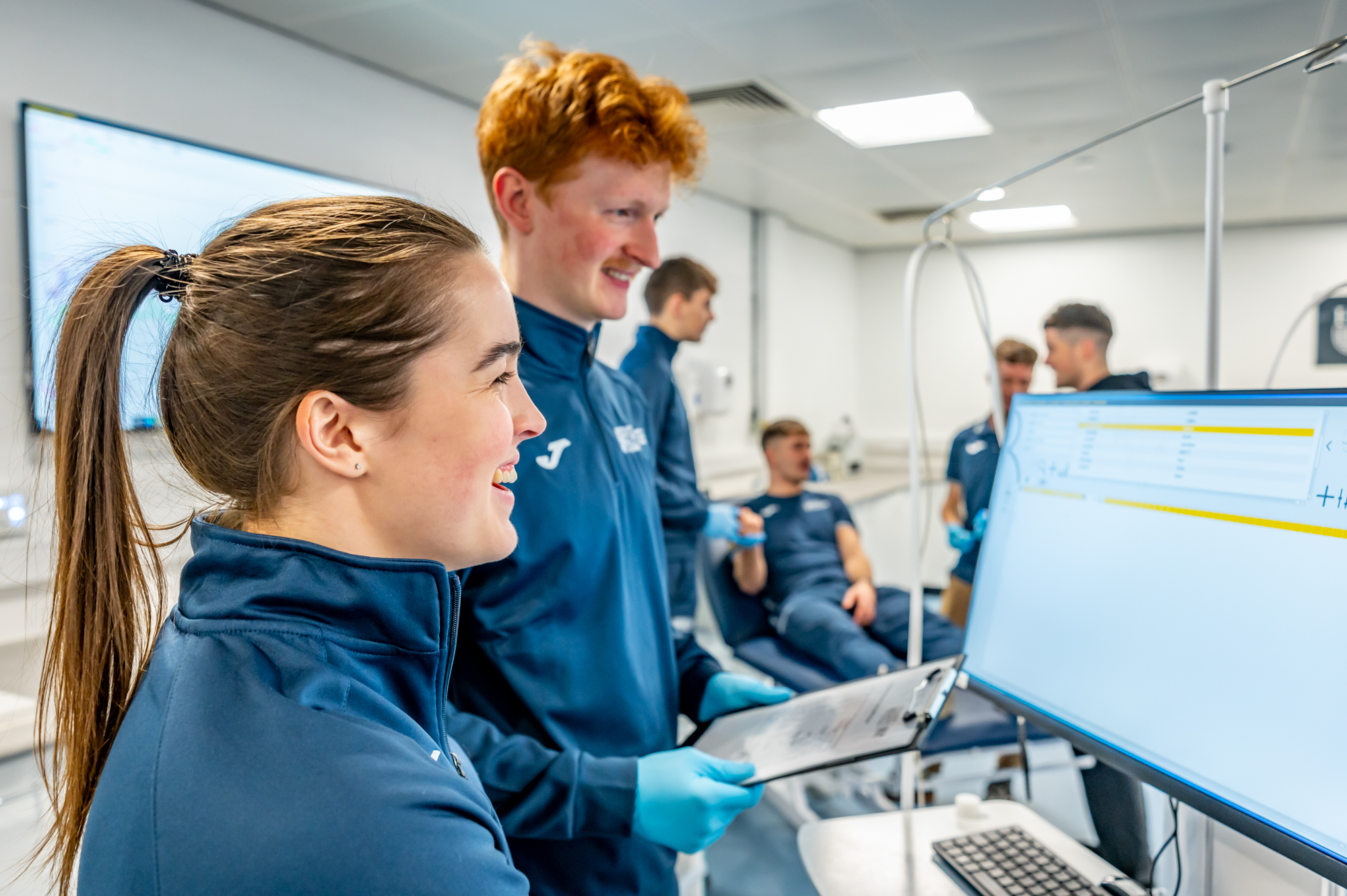 Two students looking at a computer monitor with results of a sporting performance