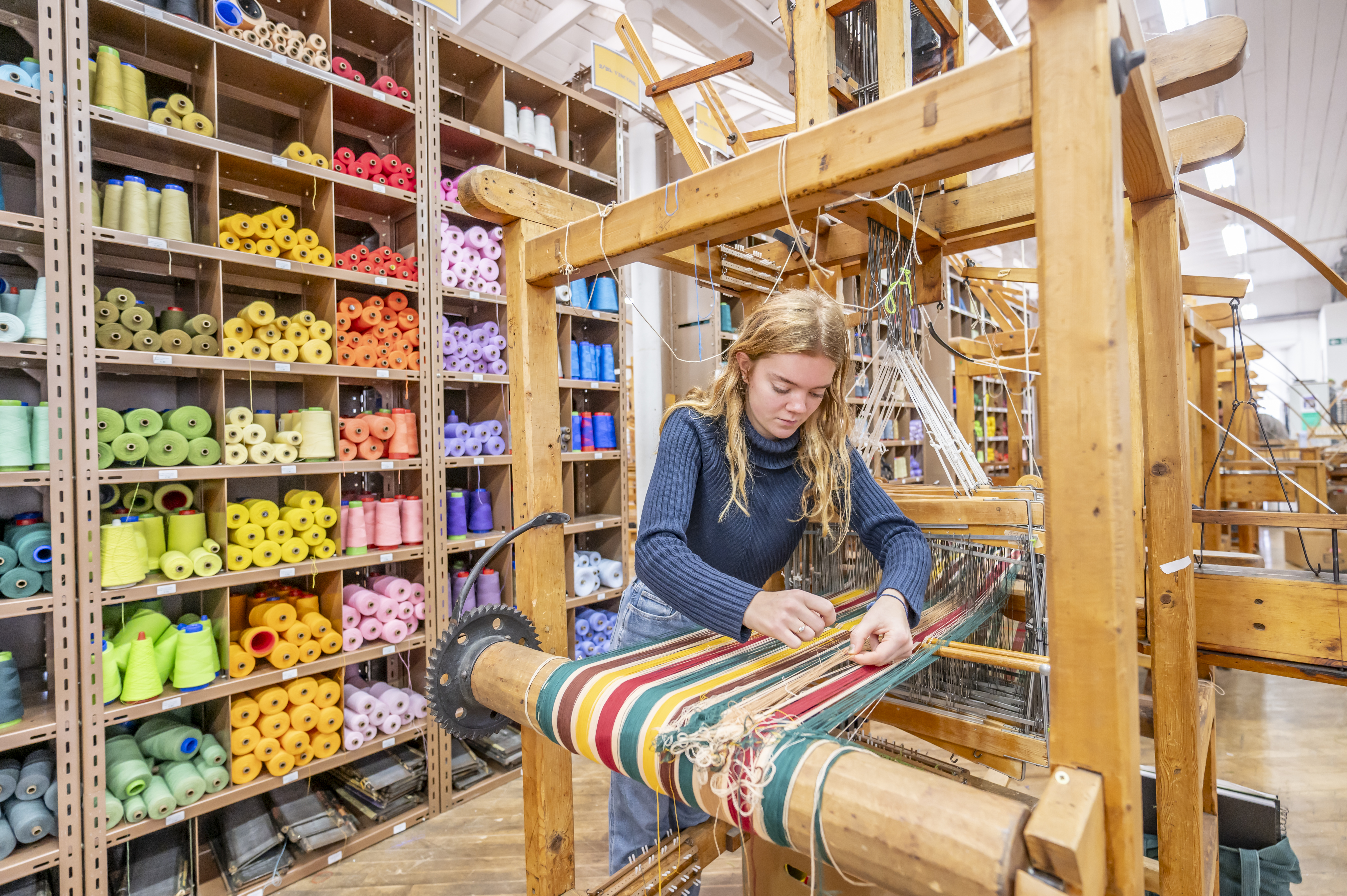 Textiles student working with a loom in the Weave Shed