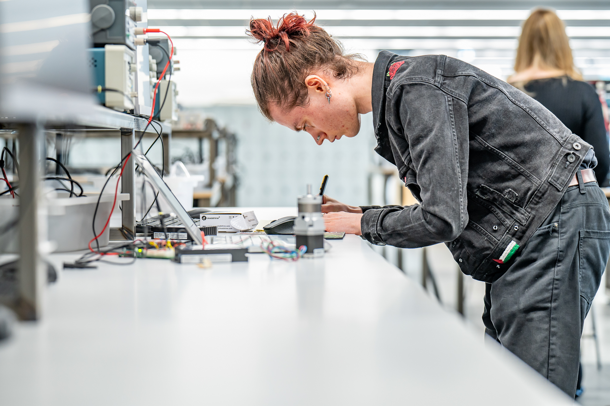 Person working on electrical equipment and laptop in a lab