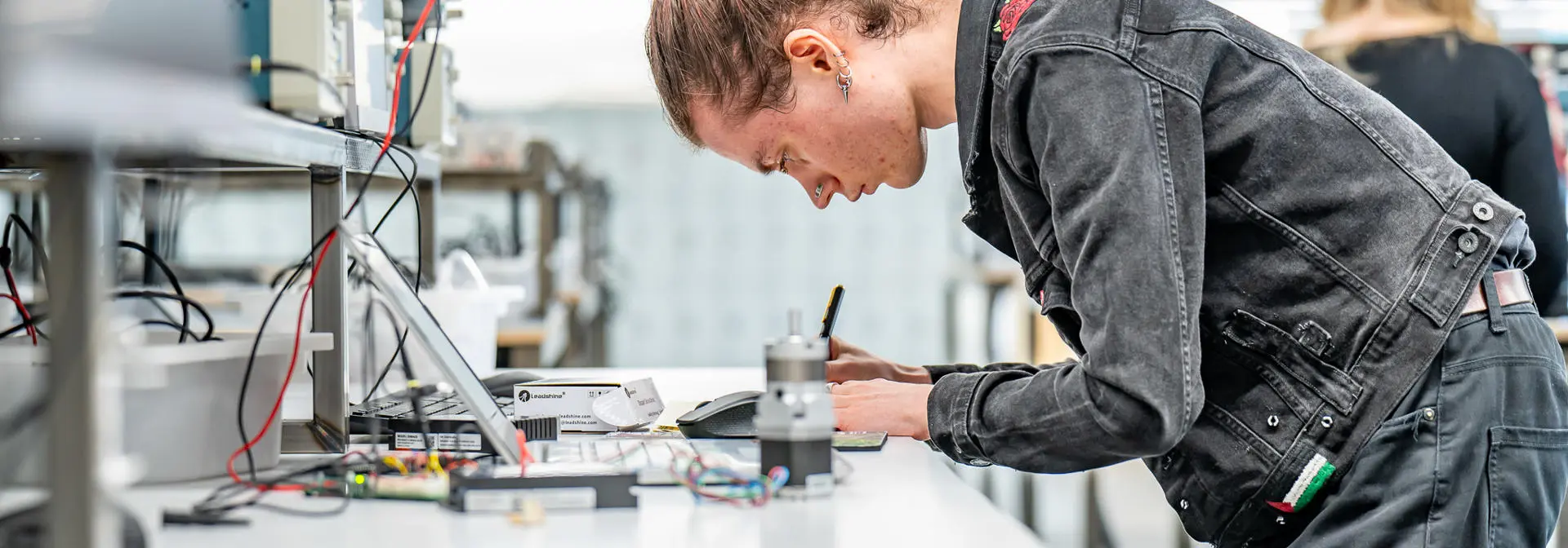 Person working on electrical equipment and laptop in a lab