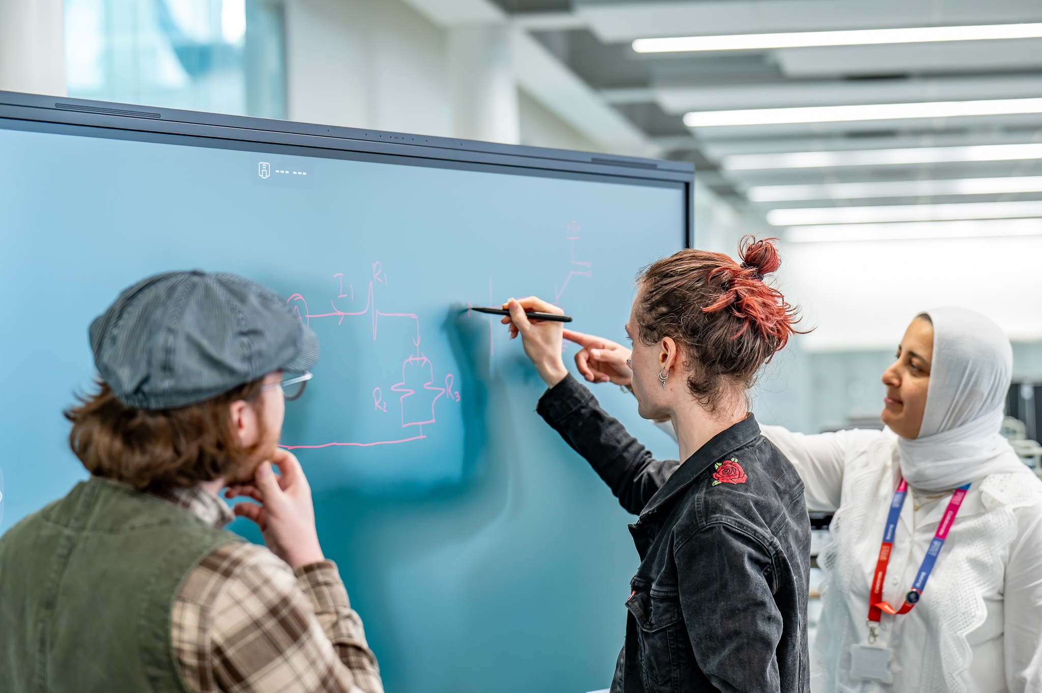 Lecturers writing on a digital blackboard for students