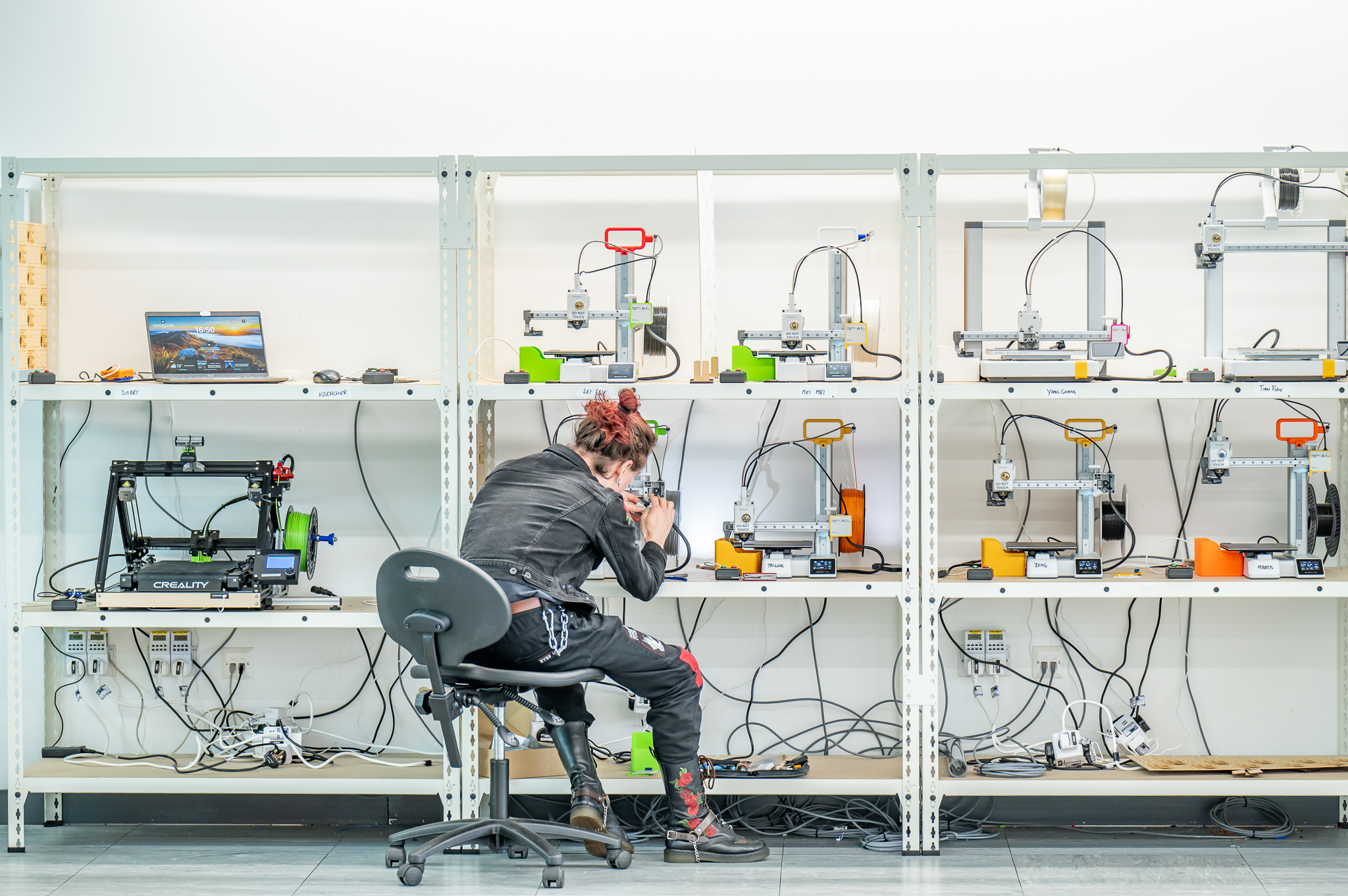 A wall of 3d printers, a person working on one of them