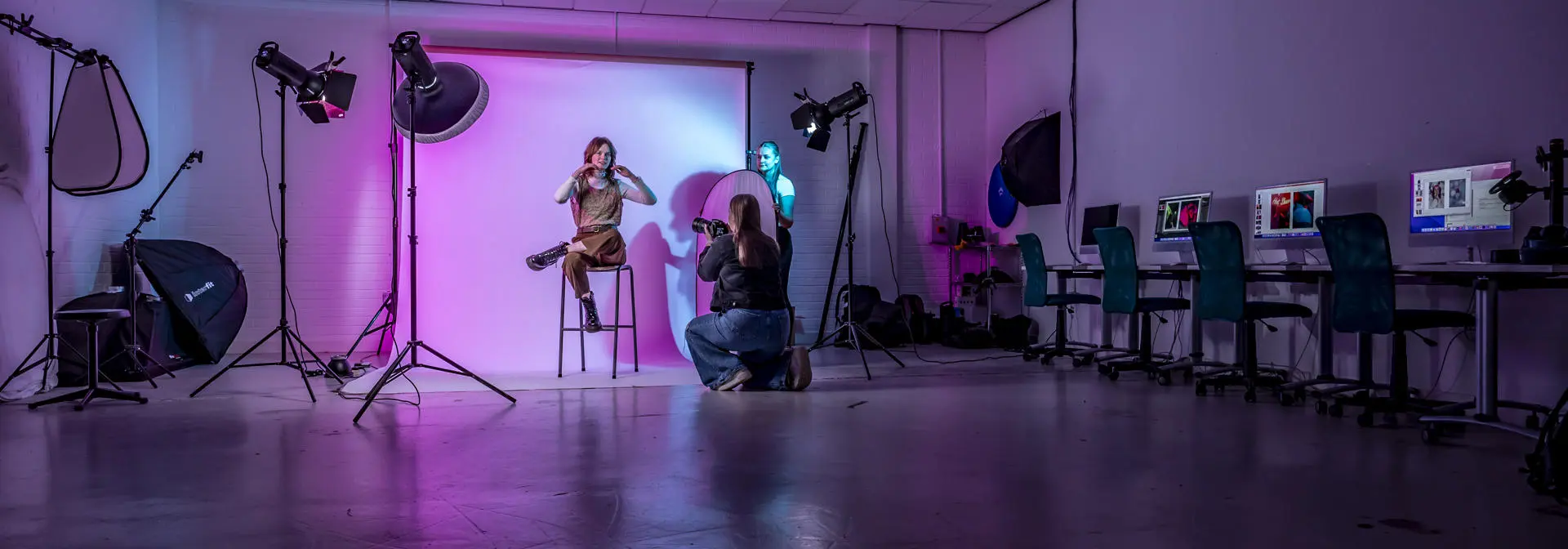 Textile and Design students taking photographs of a model against a white screen.