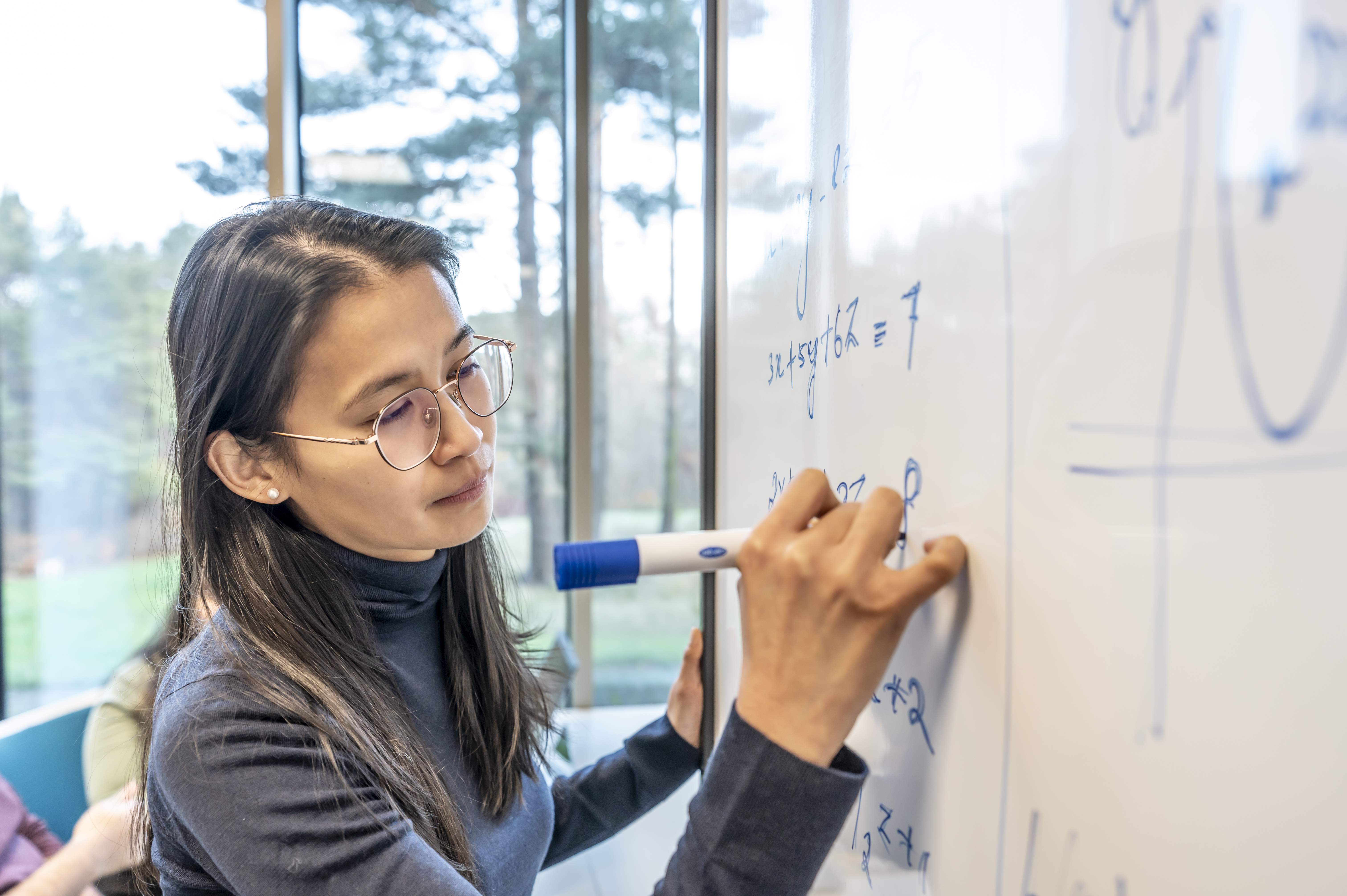 A female student completing maths equations on a white board