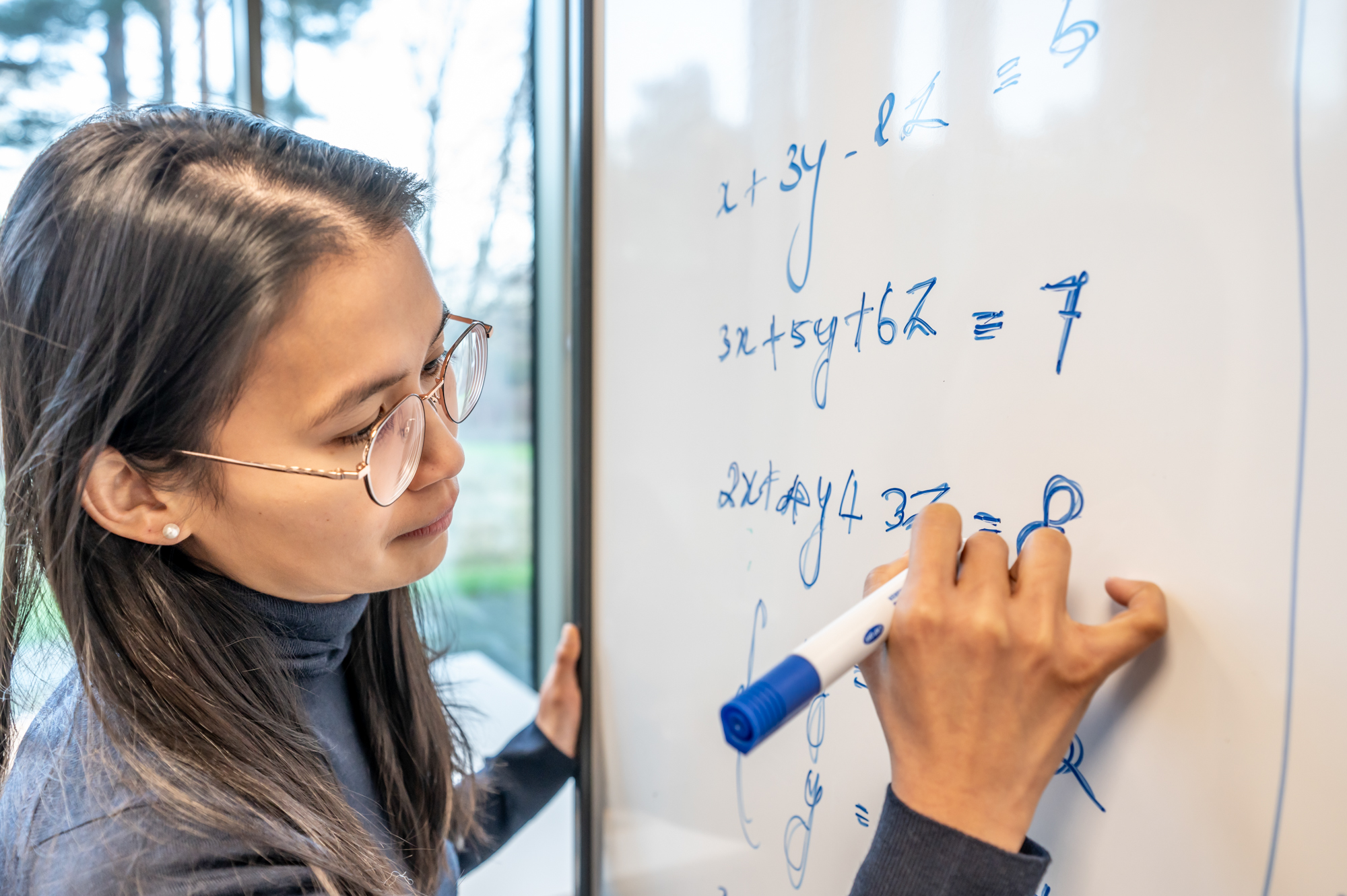Student writing mathematical equations on a whiteboard