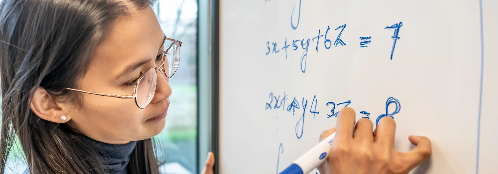 Student writing mathematical equations on a whiteboard
