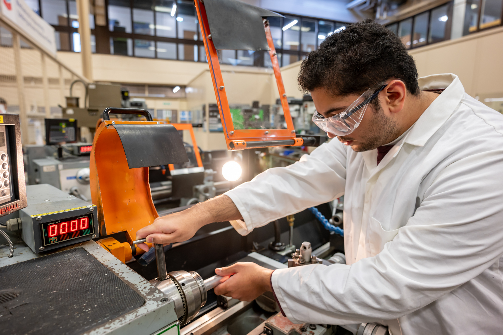 Student operating a machine with safety goggles on