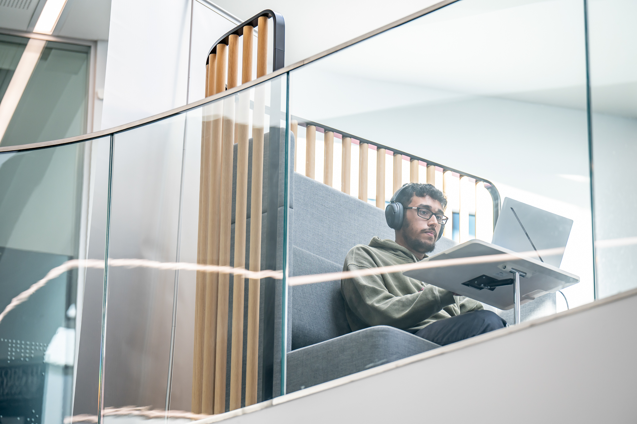 Student sitting with headphones and laptop in common area
