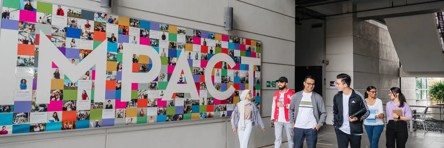 Students walking on campus with impact mural in the background