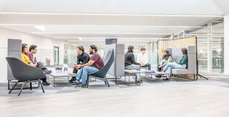 Two groups of seated students converse on the mezzanine floor of the GRID building