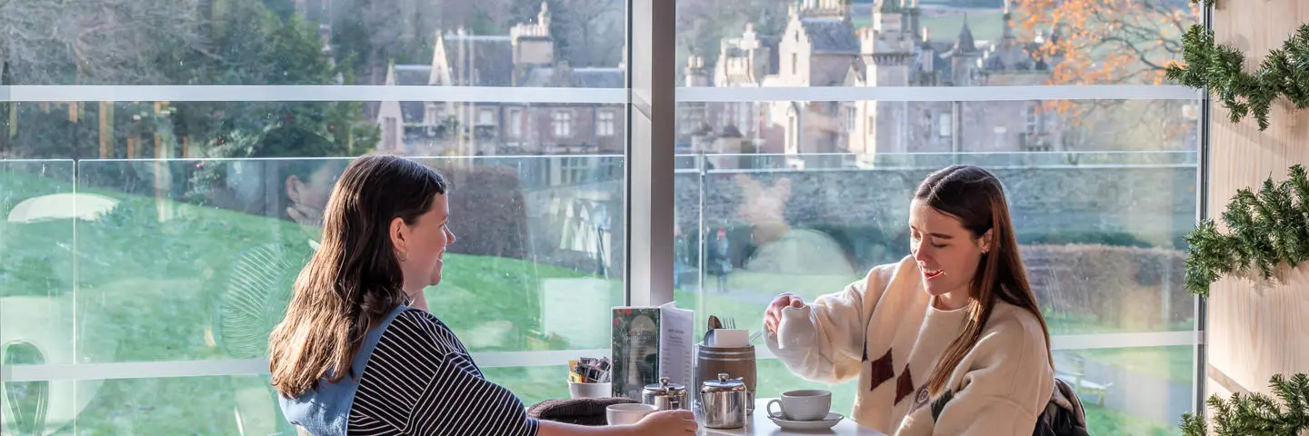 Two people sitting in a cafe drinking tea.
