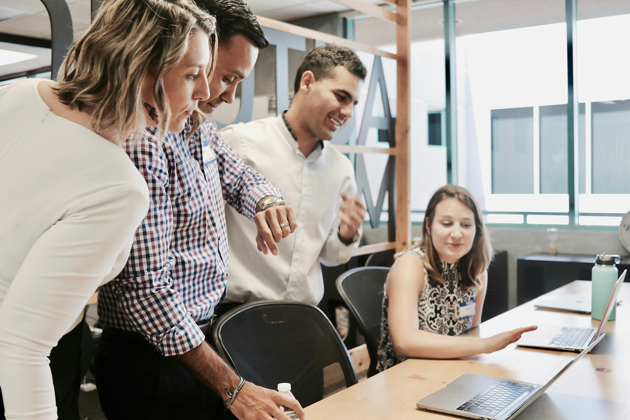 Several staff members looking at a laptop screen of a colleague