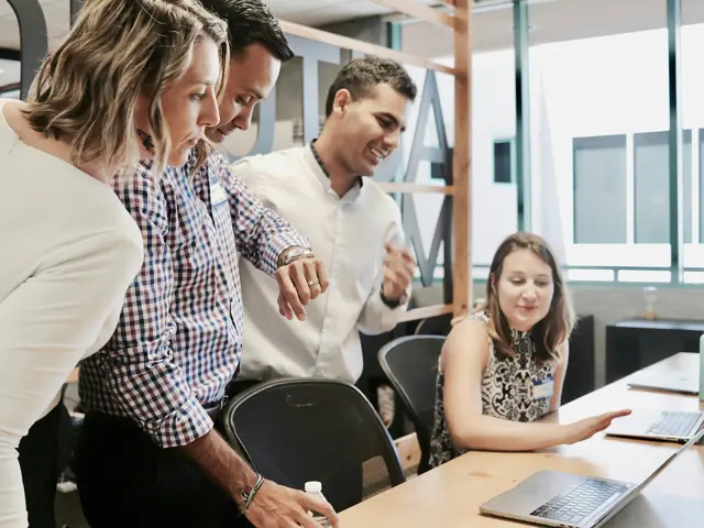 Several staff members looking at a laptop screen of a colleague