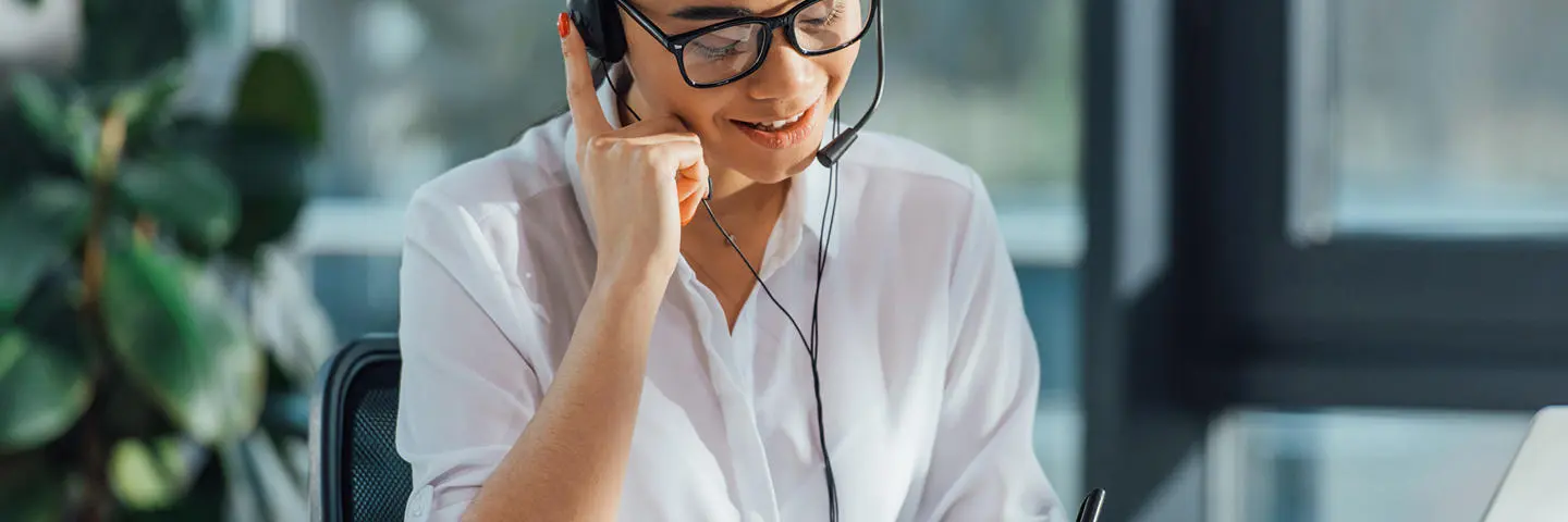 An individual working in an office listens to headphones and translates.