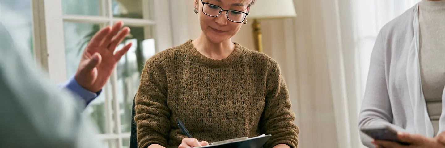 A researcher notes down on paper while in a focus group.