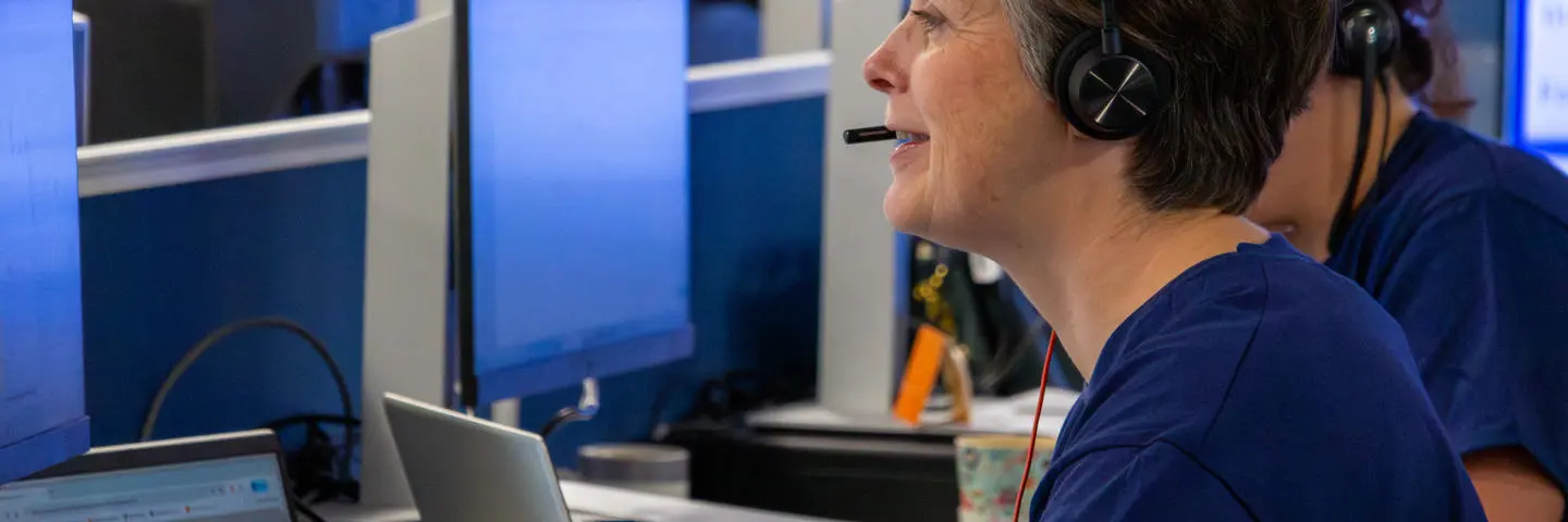 Staff working at a computer in an office with a headset.