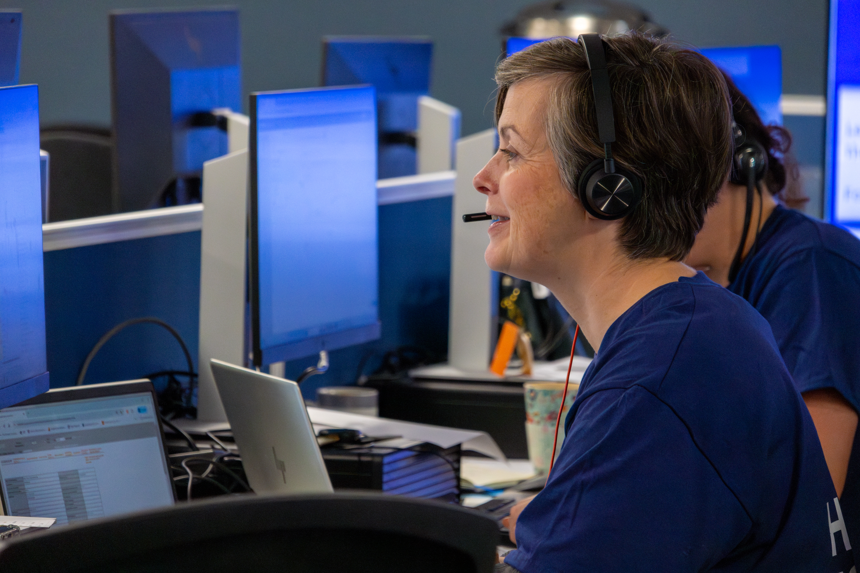 Staff working at a computer in an office with a headset.