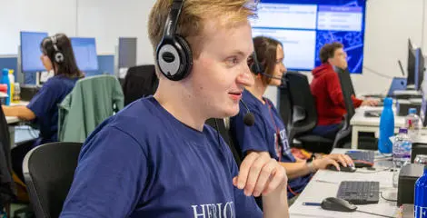 Staff working at a computer in an office with a headset.