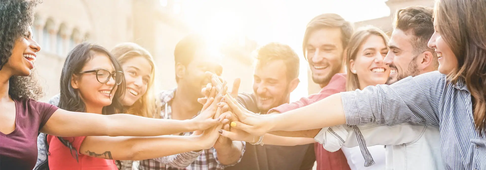 A group of young people form a circle and join hands in the middle