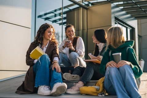 Four students sitting together drinking coffee.