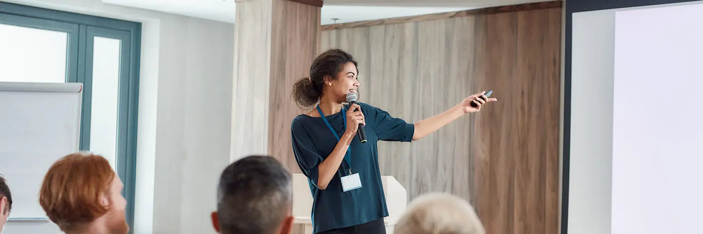 A female lecturer, presenting in front of a group.