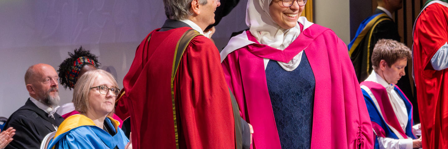A PhD graduate receives her graduation certificate at the graduation ceremony.