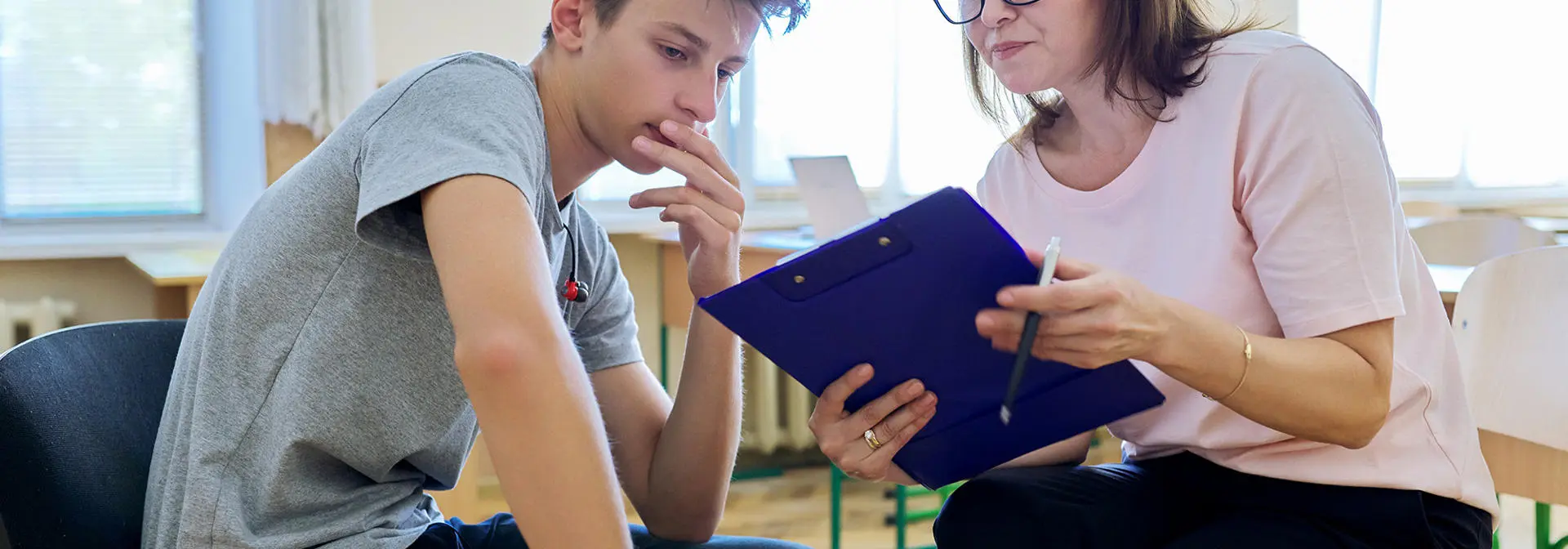 A support worker checks over a form with a young individual.