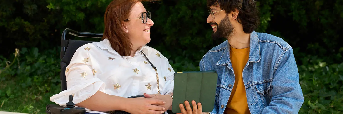 Two people smiling as they discuss over an ipad.