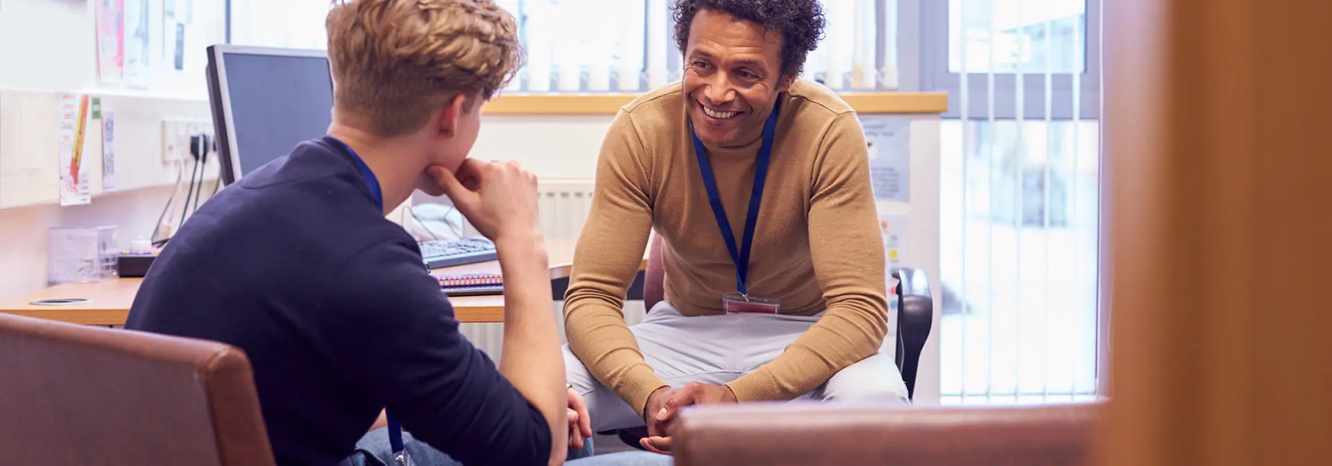 A counsellor sitting in an office talking to a student.