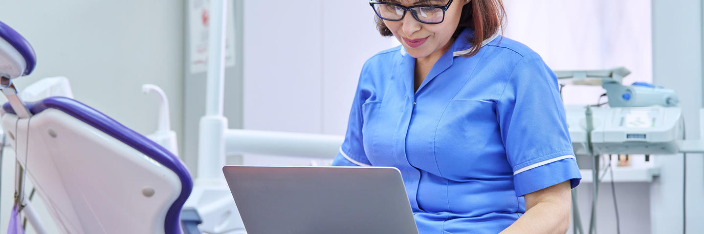 A dentist working on a laptop.