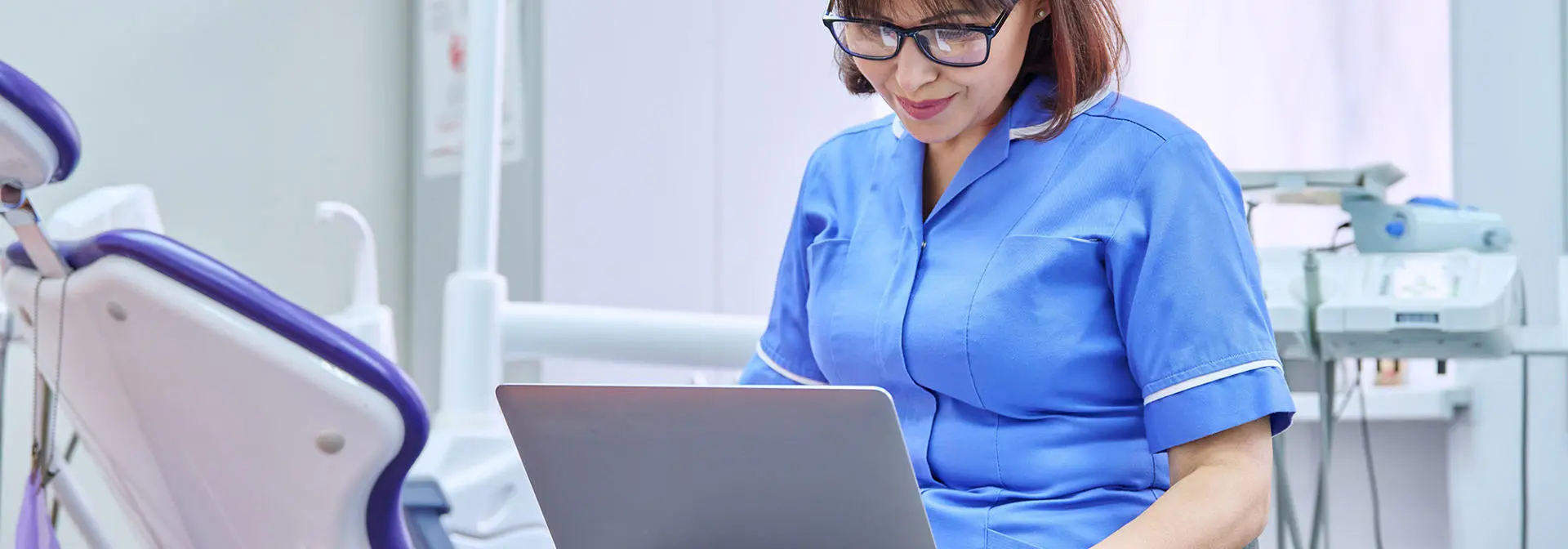 A dentist working on a laptop.