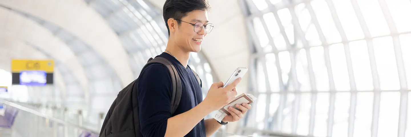 A student in an airport corridor with passport and ticket.