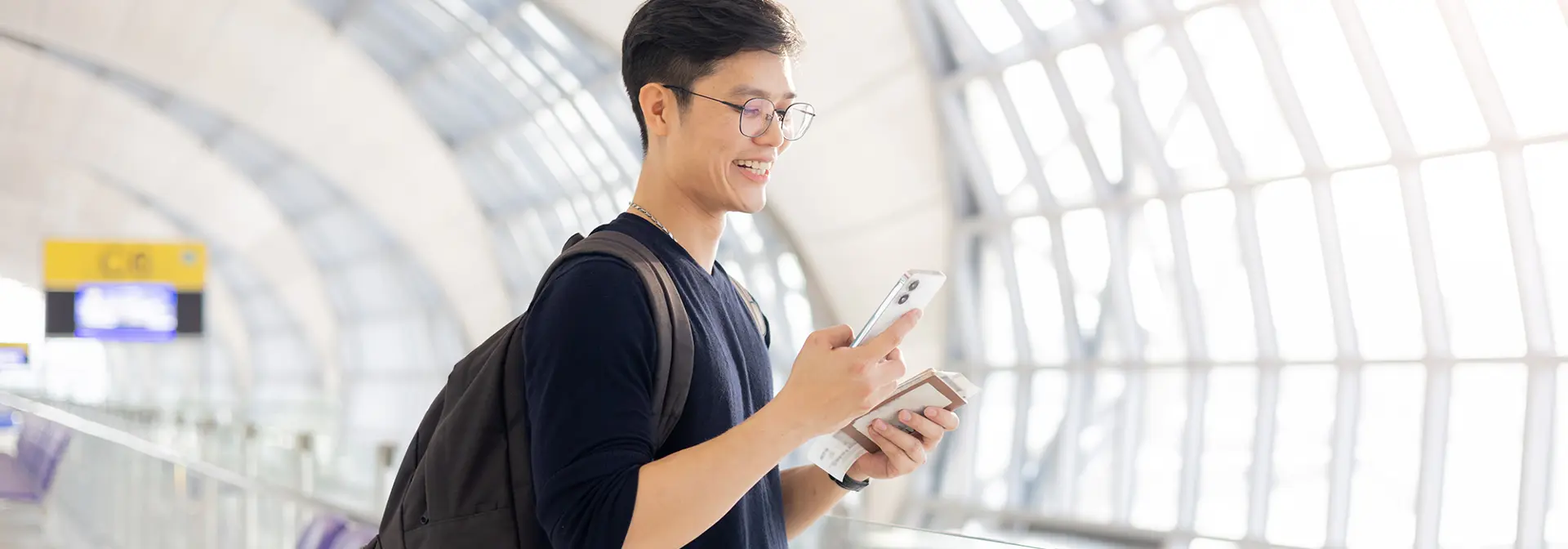 A student in an airport corridor with passport and ticket.