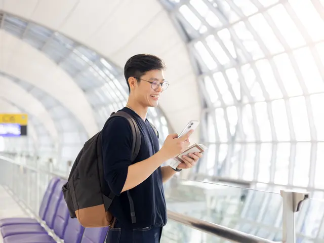 A student in an airport corridor with passport and ticket.