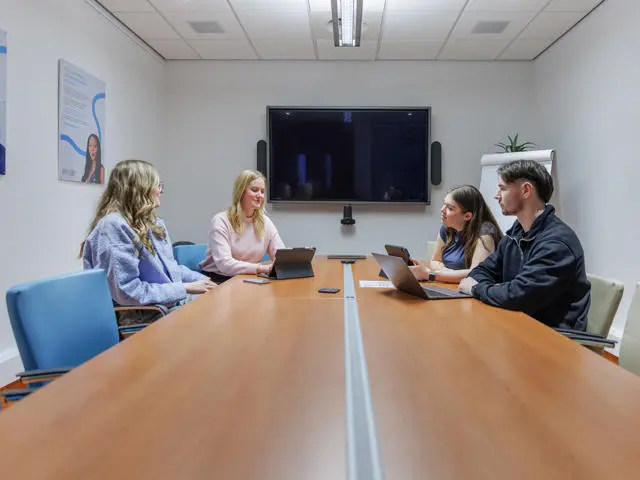 Four students sitting in the main meeting room of EBS on the Edinburgh campus.