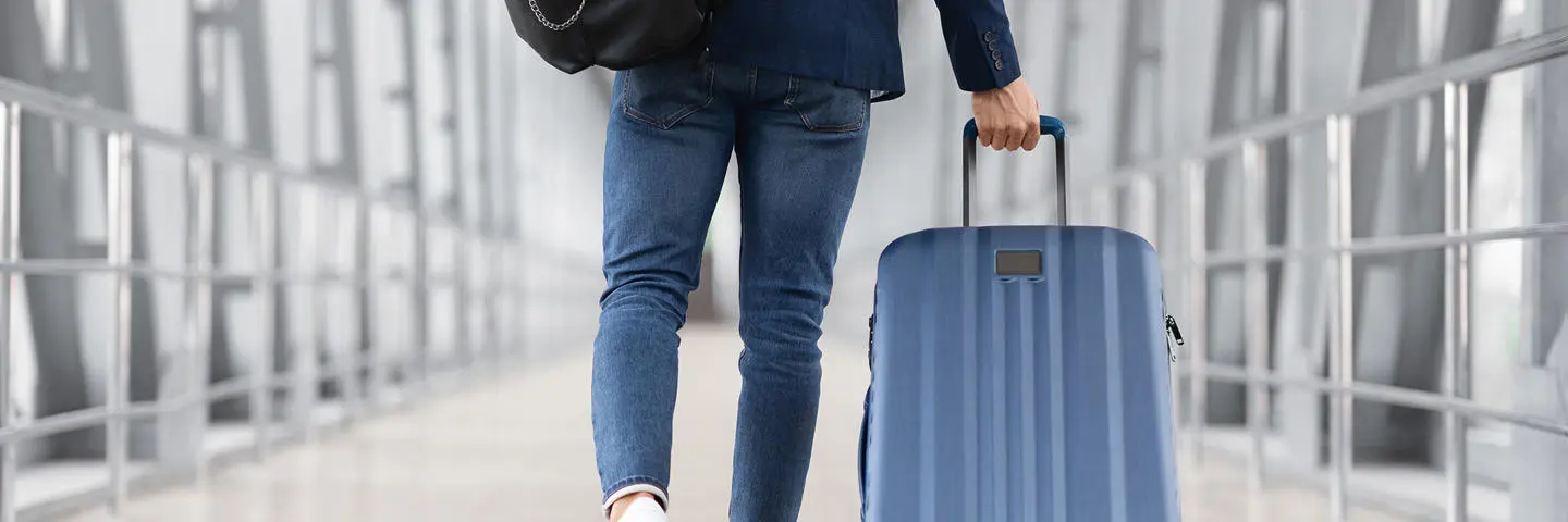 An individual taking luggage through an airport.