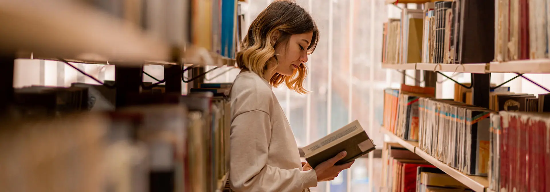 Student reading a book in a library