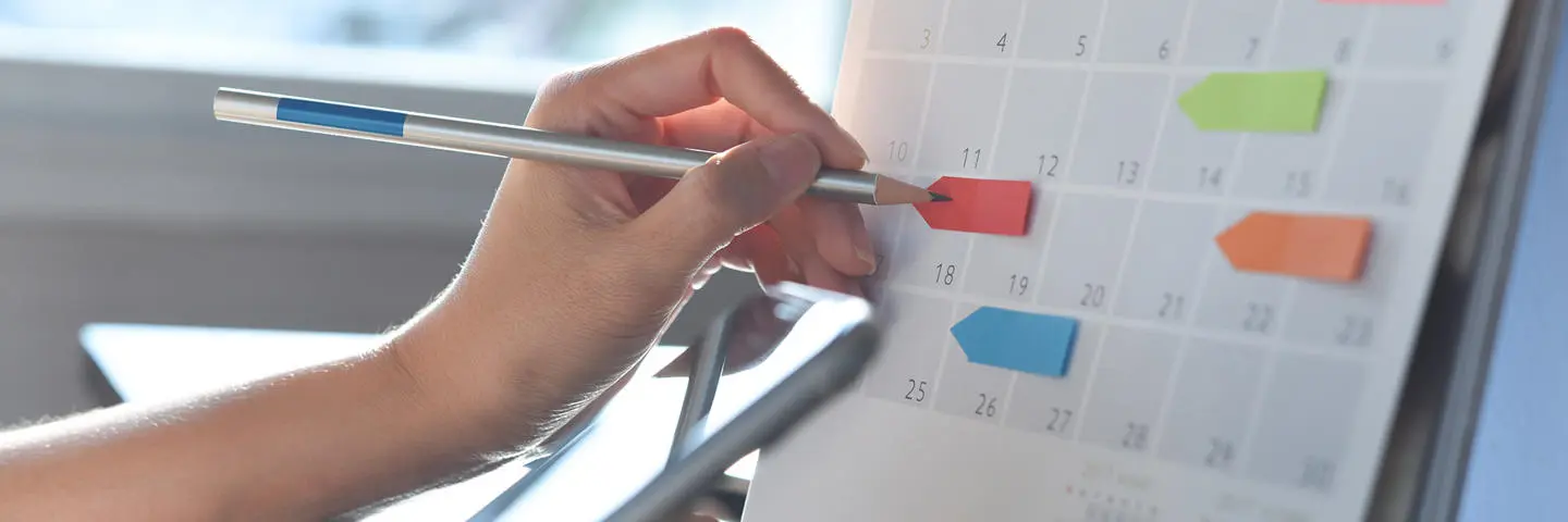 A close up of a hand writing points on a calendar.