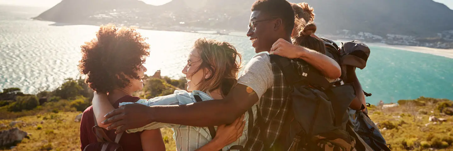 Five students in a huddle at the top of a cliff outlooking onto the sea.