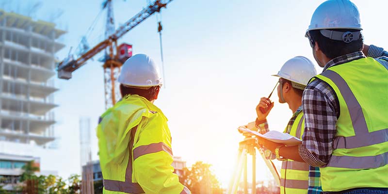 Construction managers communicate with a crane operator using a handheld radio