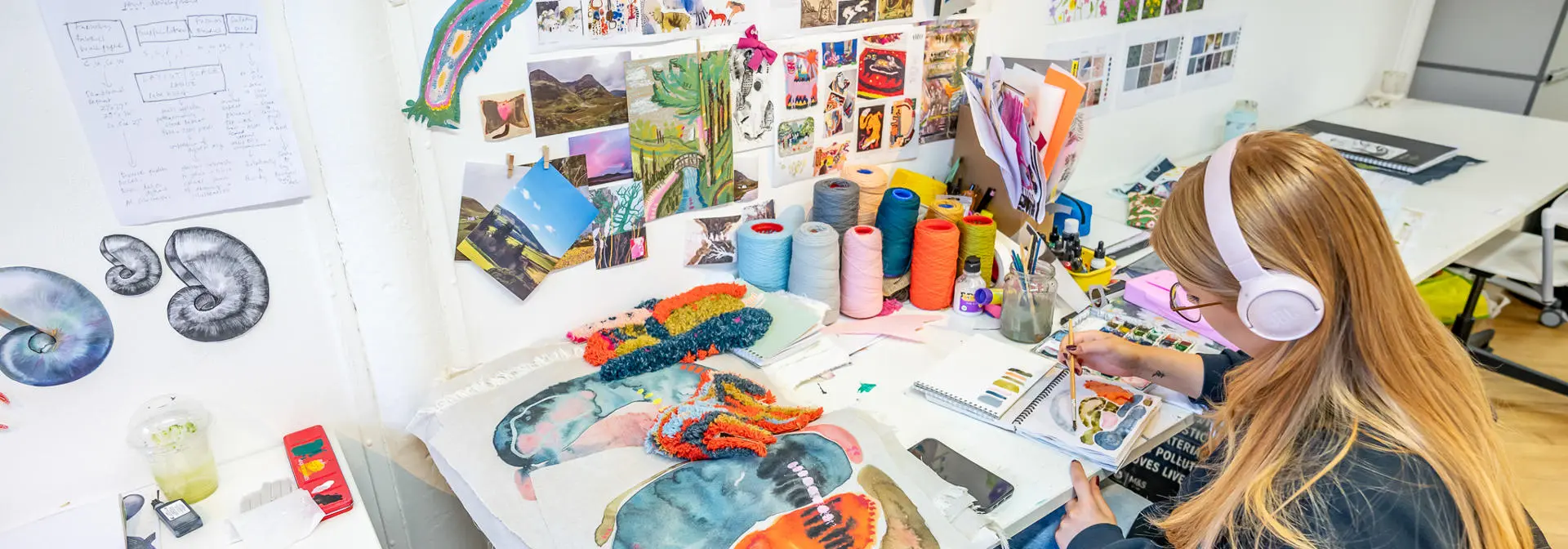 An individual paints with multiple different vibrant colours while listening to music.