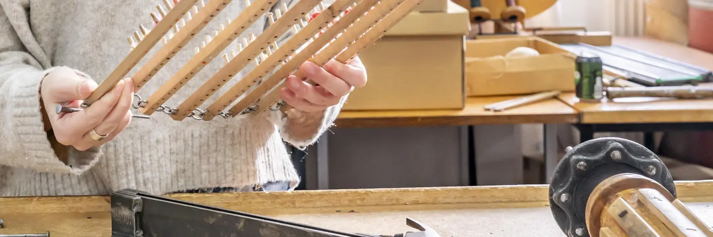 A person holds a weaving tool at a desk.