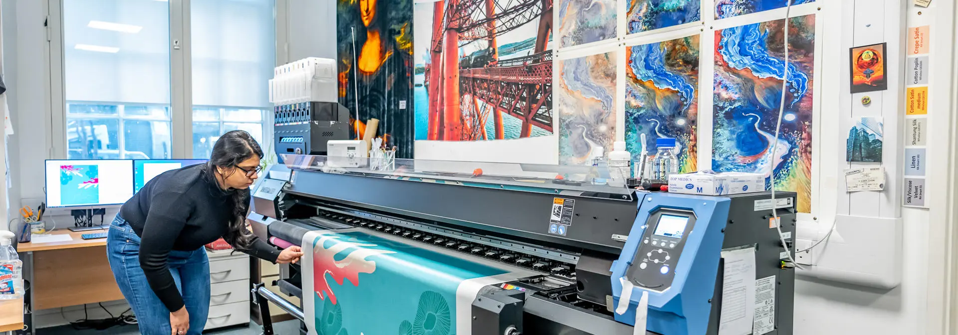 Student works on a digital print fed through a machine.