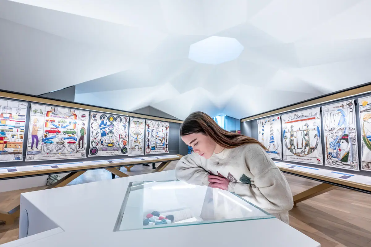 An individual in a museum, leans over a glass cabinet staring at its contents.