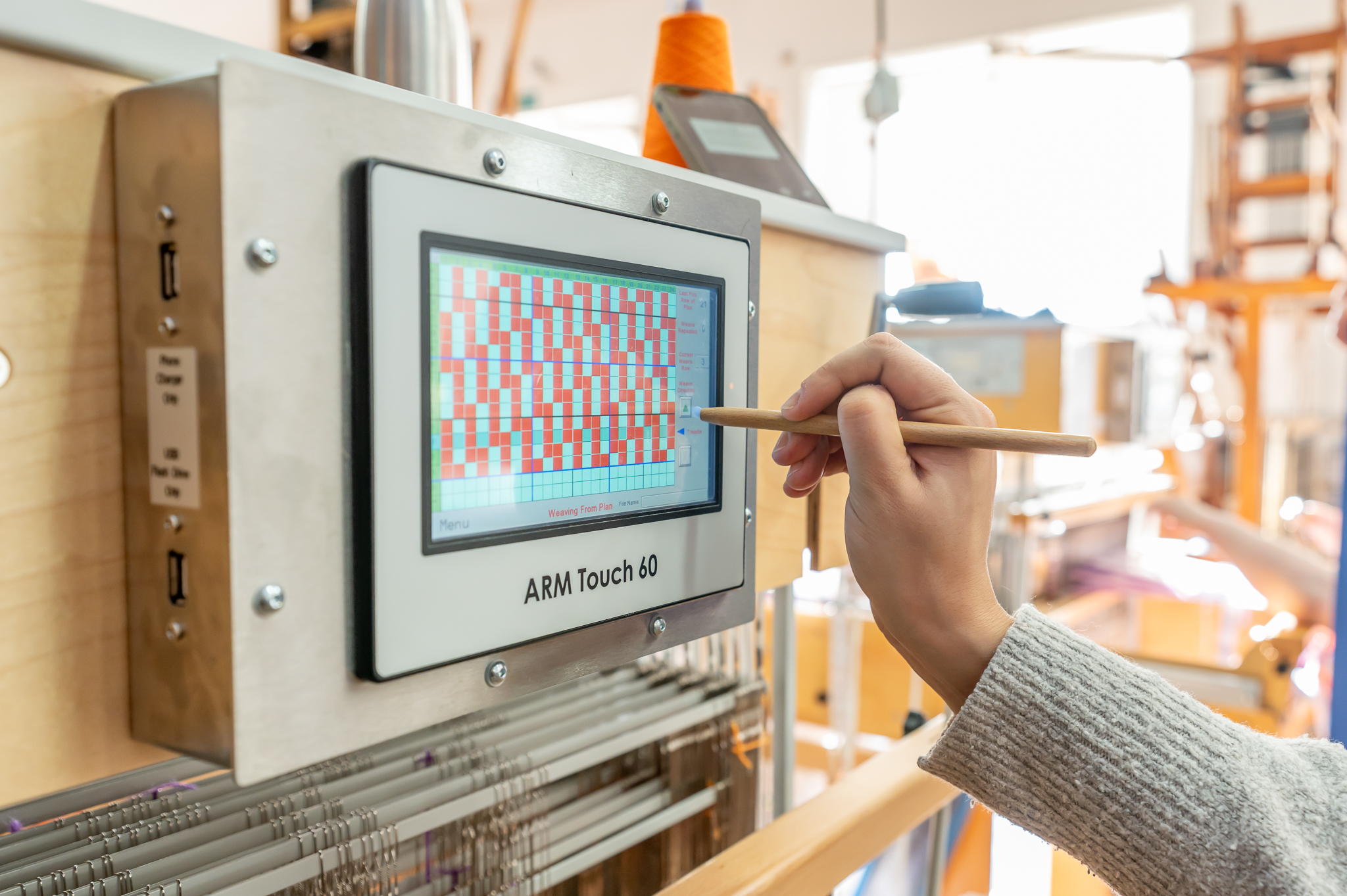 A computer screen on a weaving machine being used with a stylus.