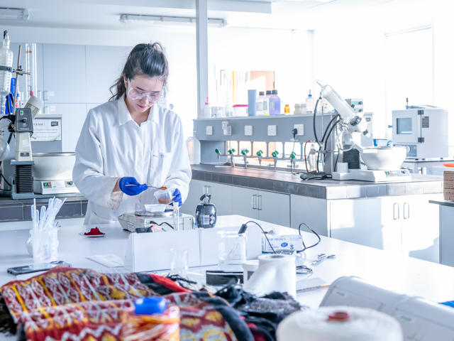 An individual measures coloured dye into a beaker in a chemistry laboratory.