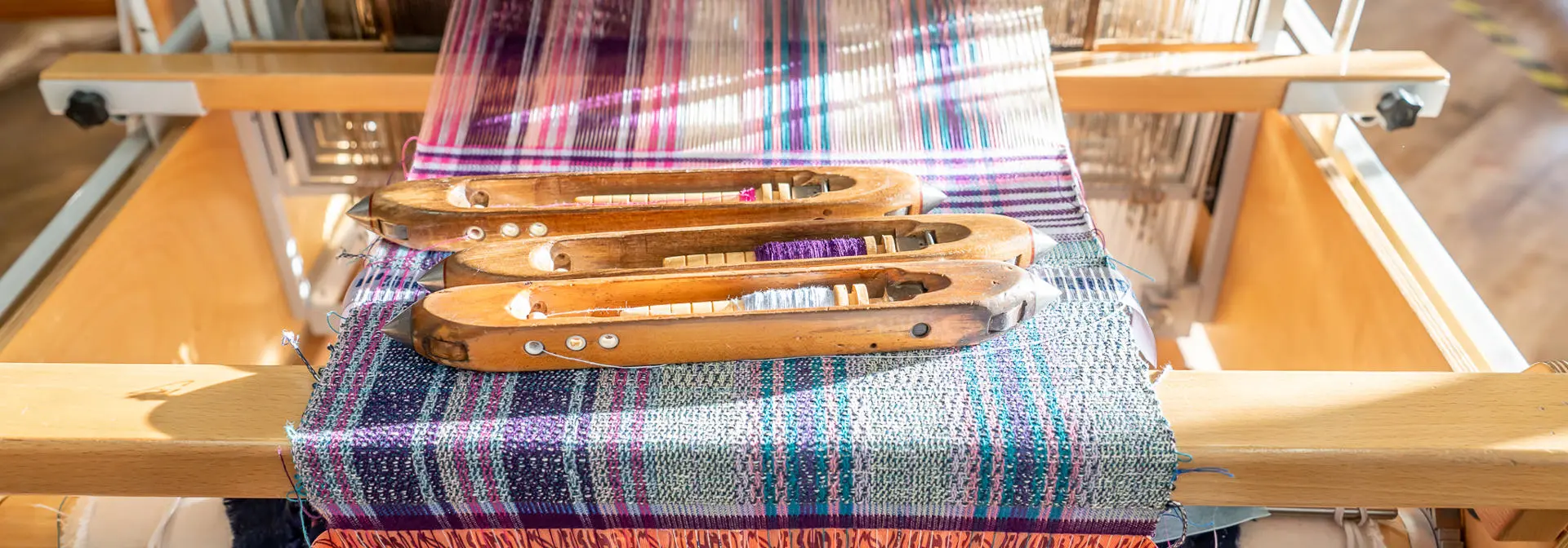 Three weaving tools placed upon a woven threaded material.