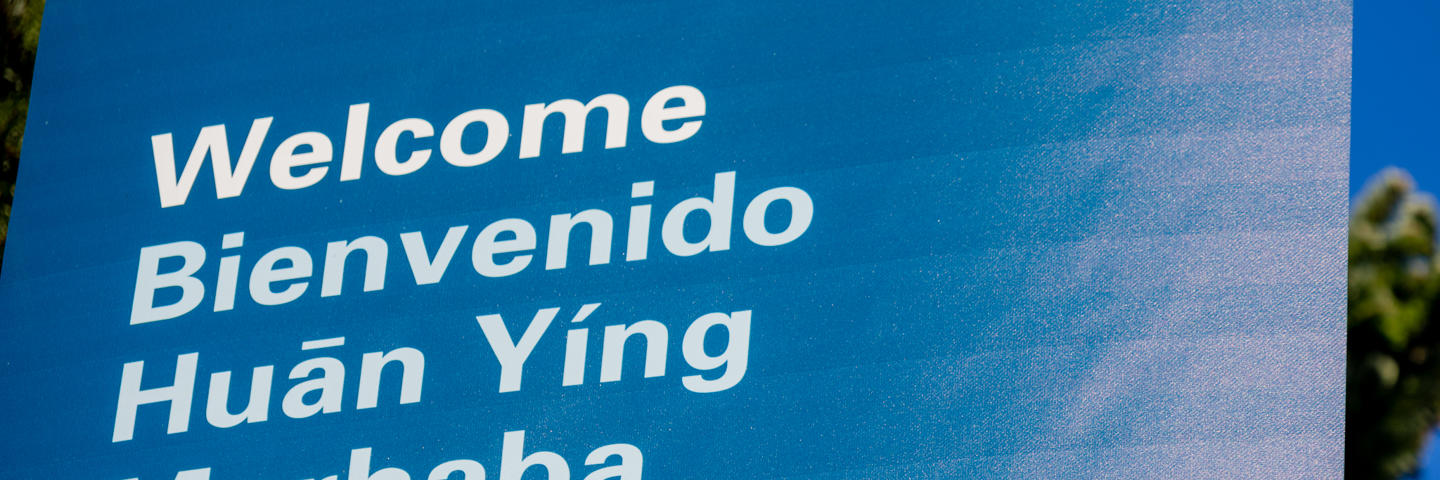 A blue sign with the word welcome written in different languages.
