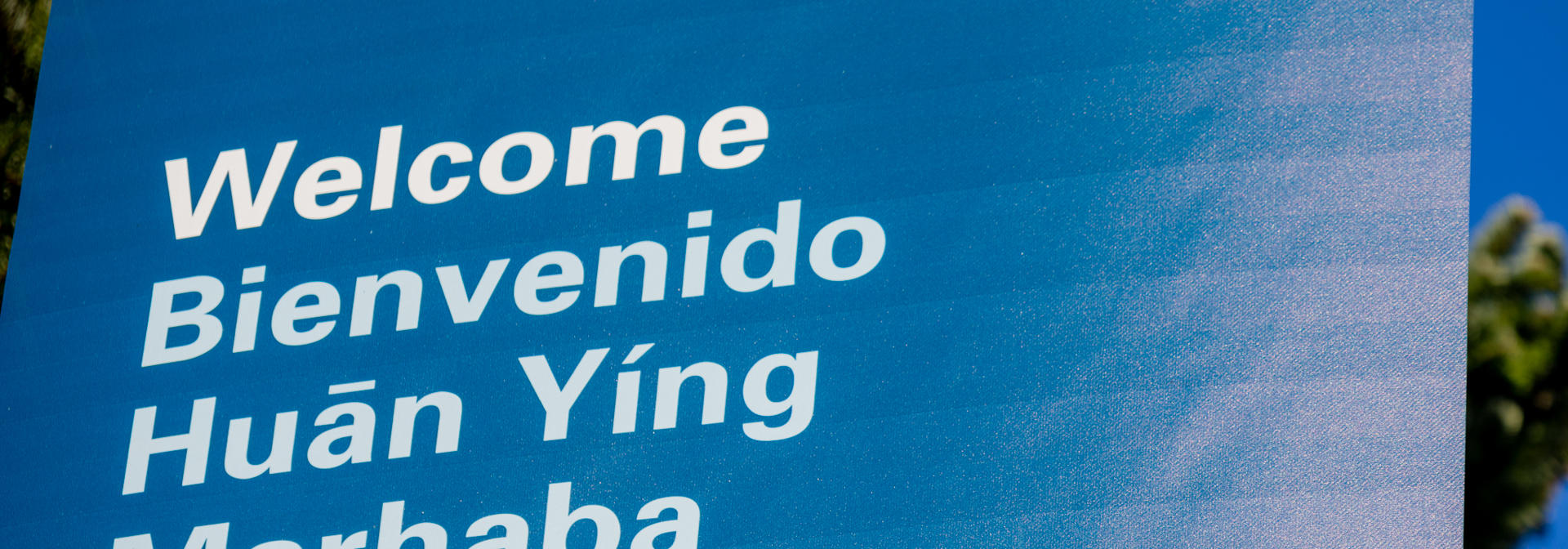 A blue sign with the word welcome written in different languages.