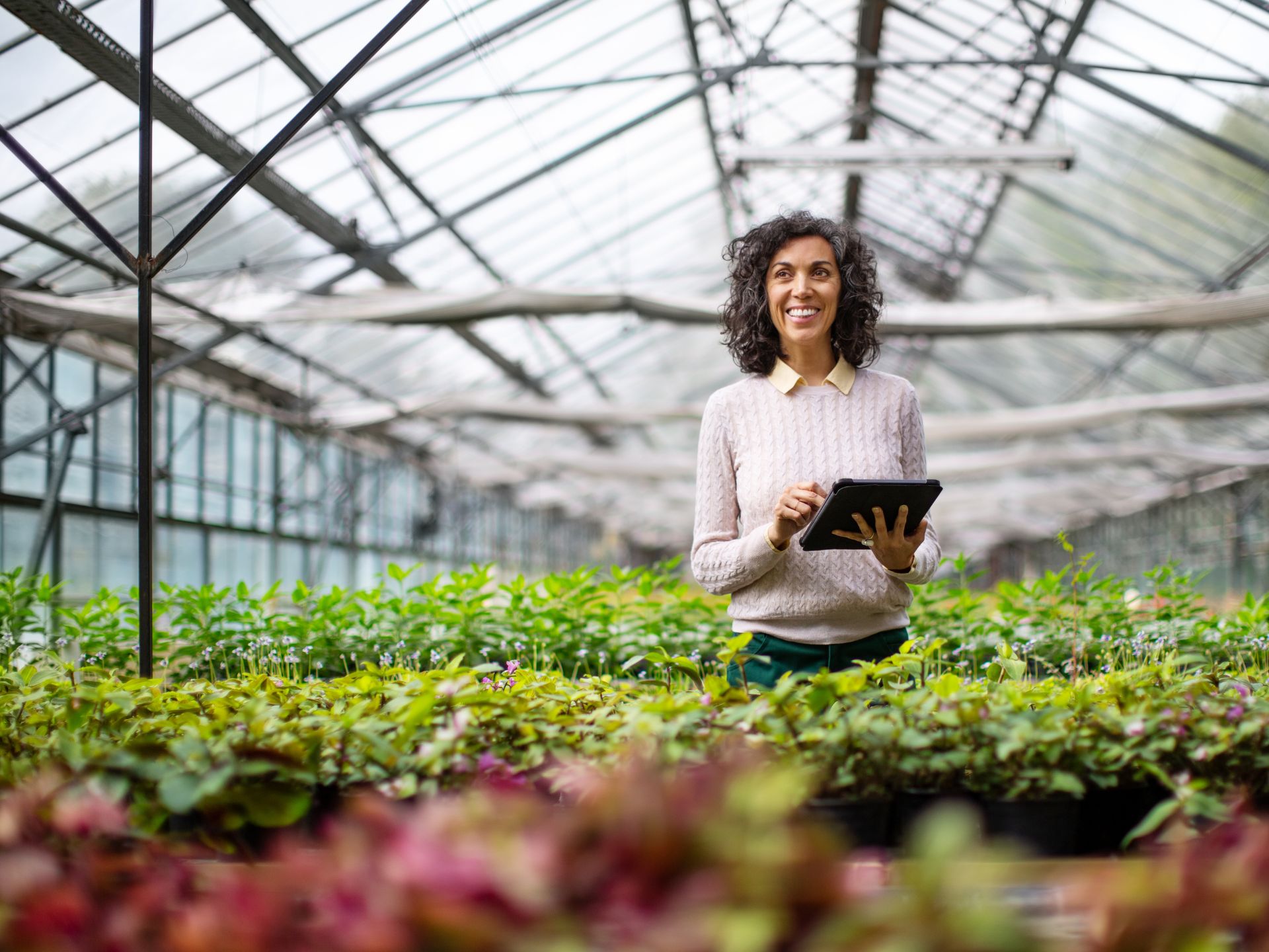 A woman standing in a greenhouse checking on plant growth 